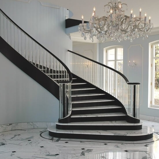 Glass balusters, marble treads, and black risers for a contemporary staircase.